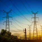 Sun setting behind the silhouette of electricity pylons