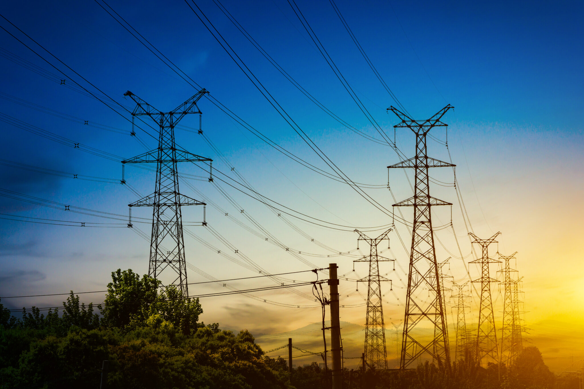 Sun setting behind the silhouette of electricity pylons