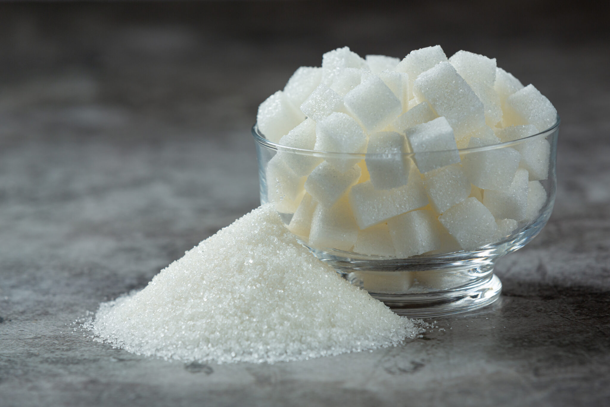 World diabetes day;
Sugar cubes in a glass bowl on dark floor